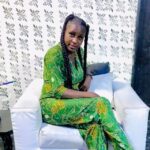 Dark skinned lady in green dress sitting on a chaire